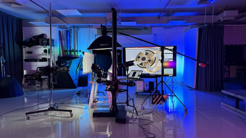 The studio rigged for a jewelry shoot: camera stand, softboxes and a gold ring on the tethered screen under blue light.