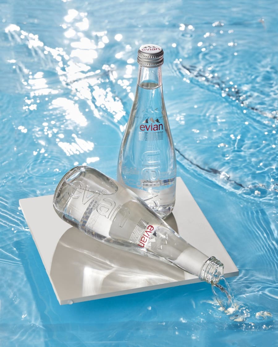 Glass water bottles photographed in a sunlit pool with real ripples.