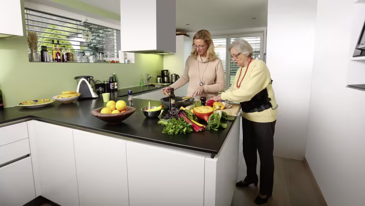 Christa trägt die Rückenorthese Dyneva, während sie in der Küche steht und das Essen zubereitet.