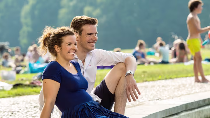 Marije and her boyfriend sit on the edge of a fountain and let their legs dangle in the water.