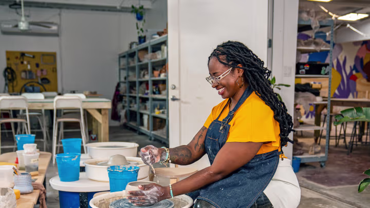 The C-Leg user is sitting on a chair while making pottery.