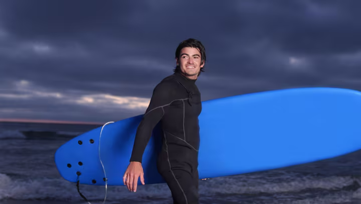 Genium X4 user Caleb carries his surfboard out of the water