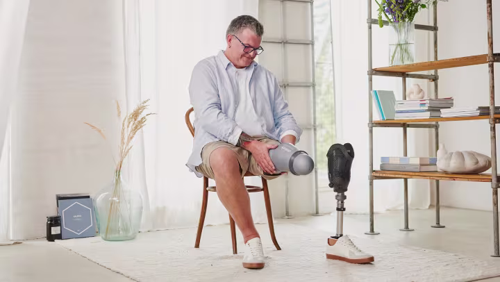 A user sits on a wooden chair and puts on his liner.