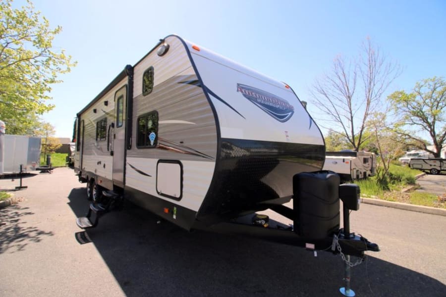 Modern Shasta travel trailer, perfect for an RV rental. Parked outdoors on a sunny day with steps extended.