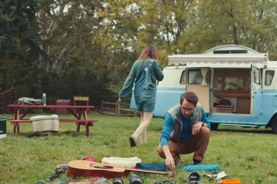 Enjoying an RV rental trip! A man organizes gear next to a retro camper van at a scenic campsite.