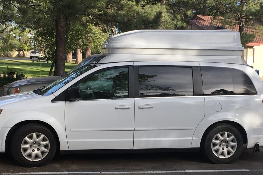 White high-top camper van, possibly for RV rental, parked. Ideal for travel & adventure.