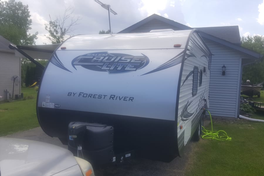 A Salem Cruise Lite by Forest River travel trailer (RV) parked with awning extended. An RV rental option for camping trips.