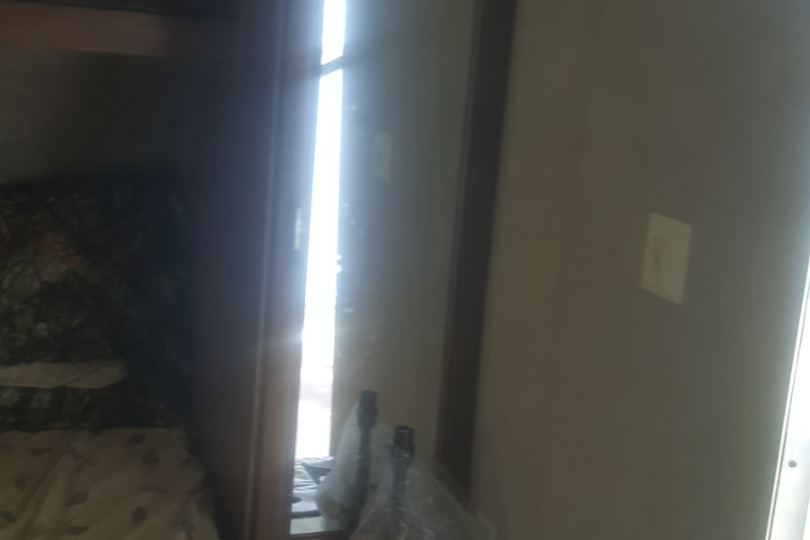 RV rental: a cozy bedroom with patterned bed, mirrored wardrobe, and compact counter with remote.