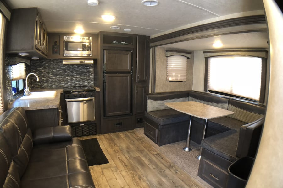 Spacious rv rental interior featuring a full kitchen, comfy sofa, and dinette. Perfect for your next adventure!