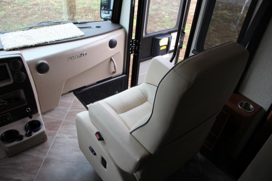 Spacious Forza RV rental interior: view of driver's cockpit with plush leather seat, modern dashboard, and tiled floor.