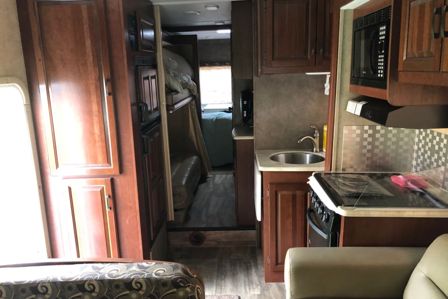 Inside this RV rental: a well-equipped kitchen, cozy bunk beds, & comfortable living area in a modern recreational vehicle.