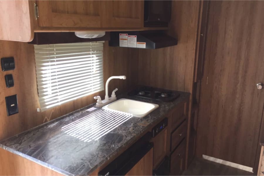 Explore this well-equipped RV rental kitchen featuring a sink, stove, microwave, and spacious countertop.