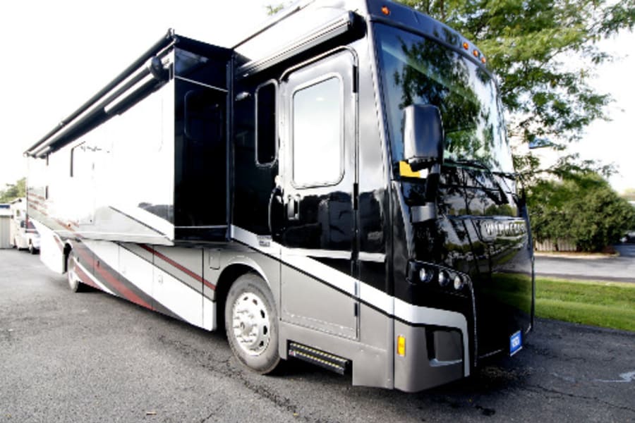 A sleek black & grey RV rental, a Winnebago motorhome, parked with slide-outs extended.