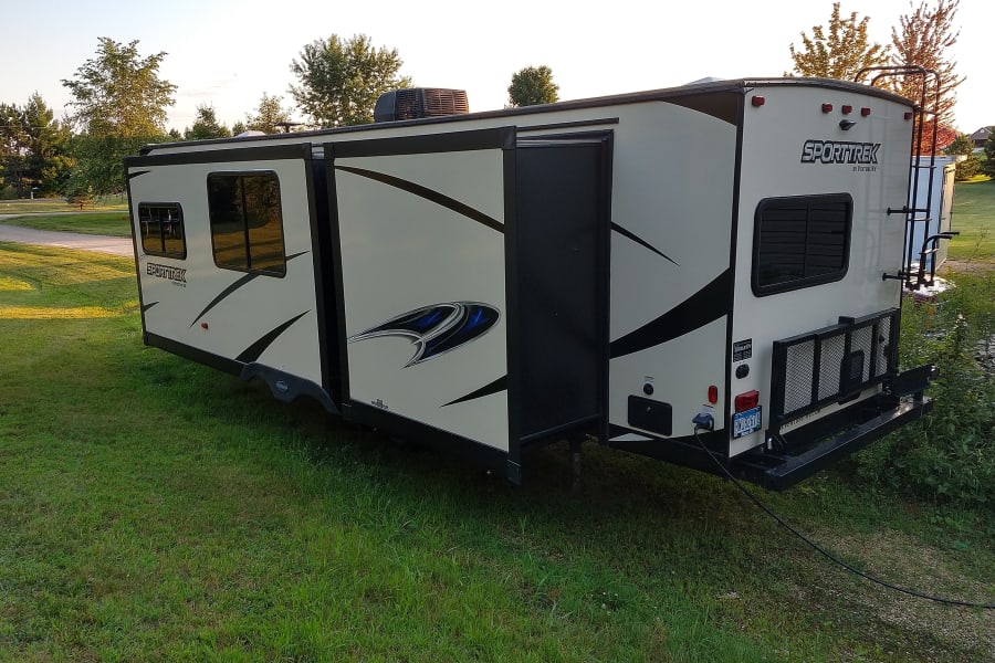 Rear of camper with a storage tray and bike rack.
