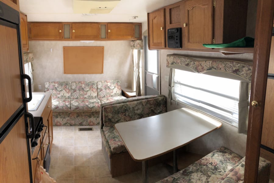 Inside this RV rental: a well-equipped kitchen, floral sofa, dinette, and overhead cabinets offer a homey travel space.