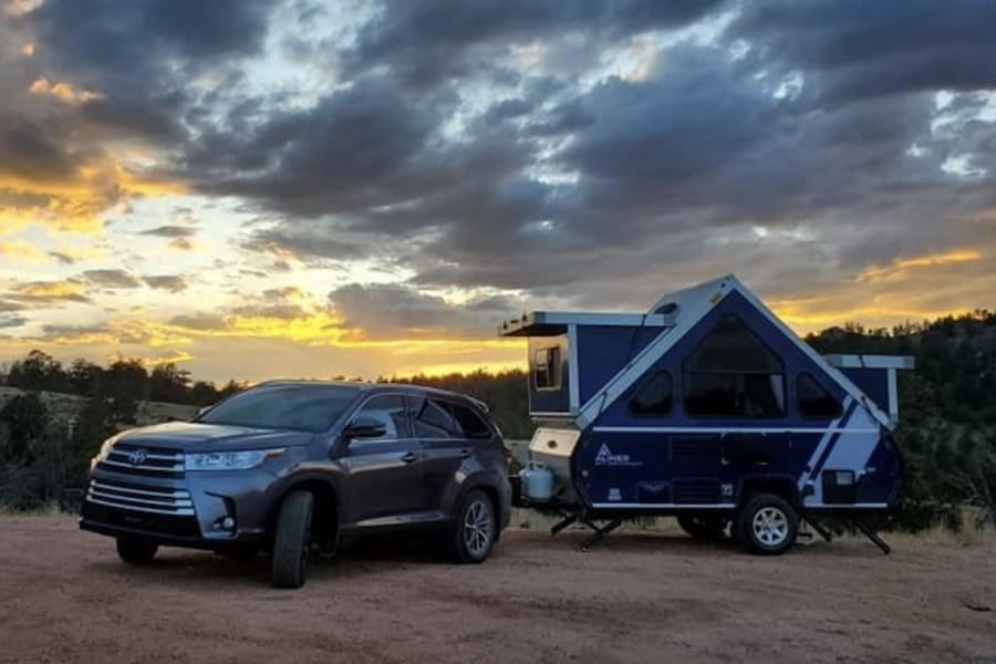 Beautiful sunset view with an SUV and A-frame pop-up camper, ideal for your next RV rental adventure.