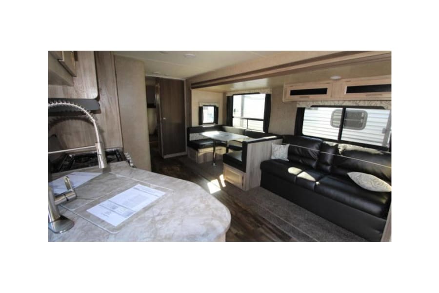 Spacious RV rental interior featuring a full kitchen, comfortable dining booth, and a cozy living room sofa.