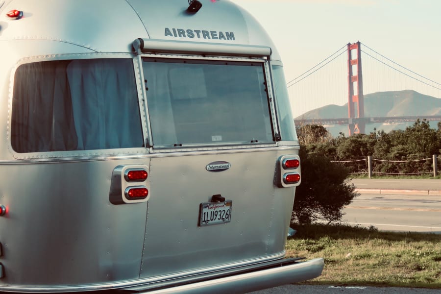 Iconic Airstream rv rental, rear view with a California plate, parked to showcase the Golden Gate Bridge.