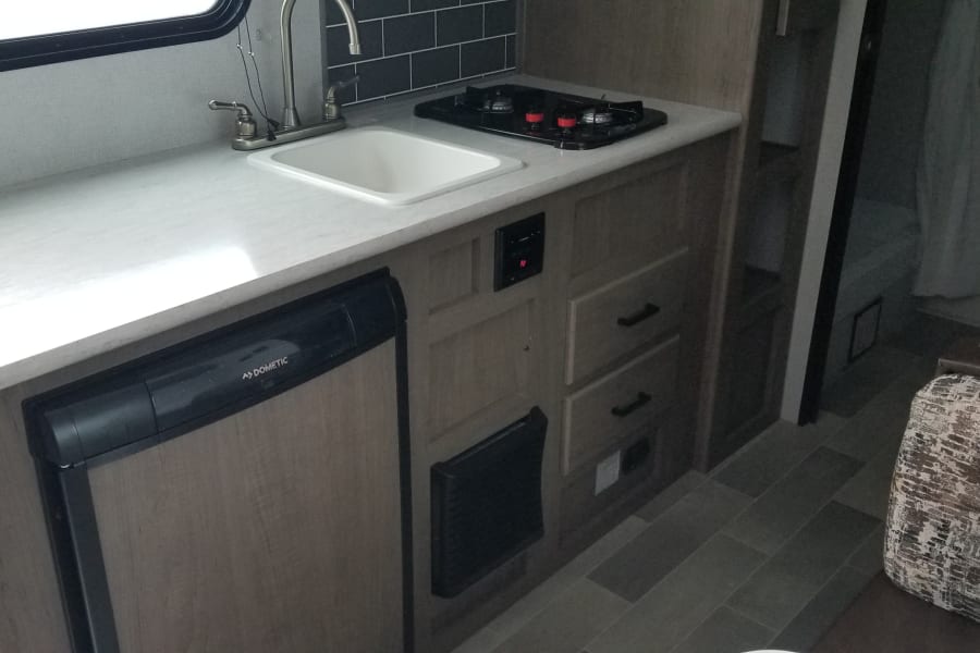 RV rental interior: Equipped with a functional kitchen (sink, stove, Dometic fridge) and a compact bathroom.