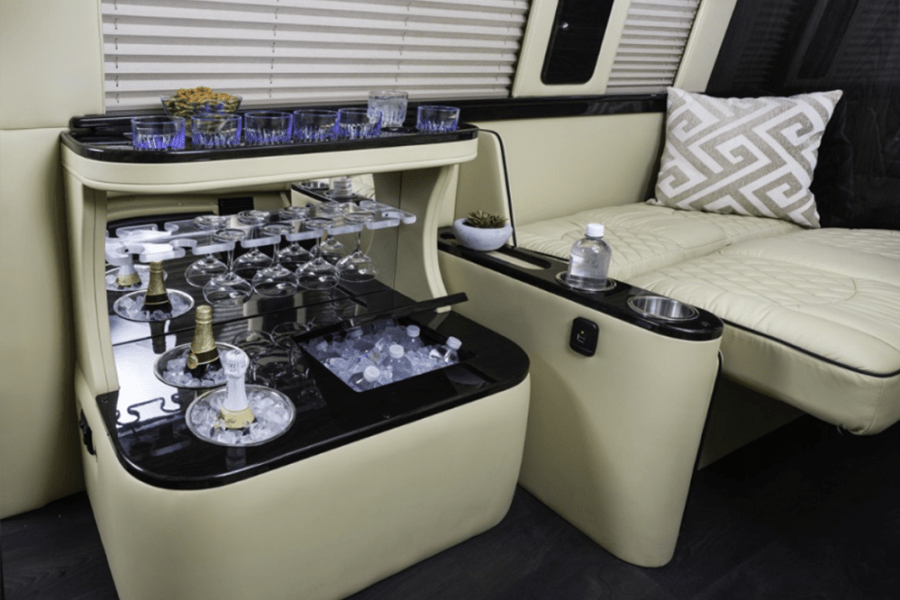 Experience luxury in this RV rental: lavish interior with a built-in bar, chilled drinks, glassware, and plush seating.