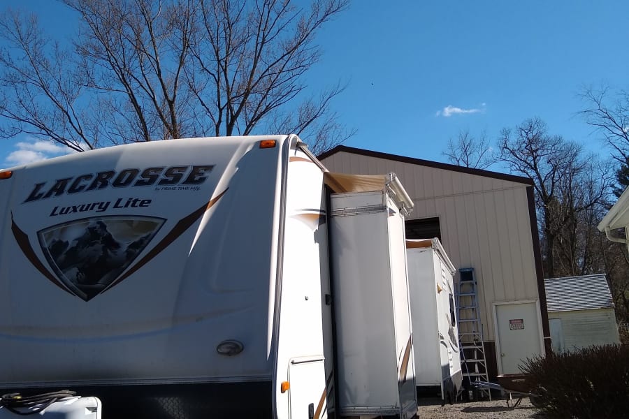LaCrosse Luxury Lite RV rental travel trailer parked with slide-out extended on gravel under a clear blue sky.