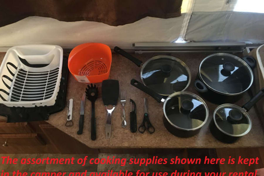 This RV rental includes a complete set of camping cooking supplies: pots, pans, utensils, dish rack, and colander.