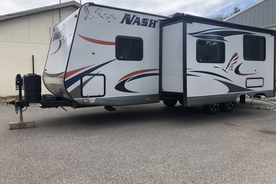 White Nash travel trailer, perfect for RV rental. Features an extended slide-out & front propane tanks.