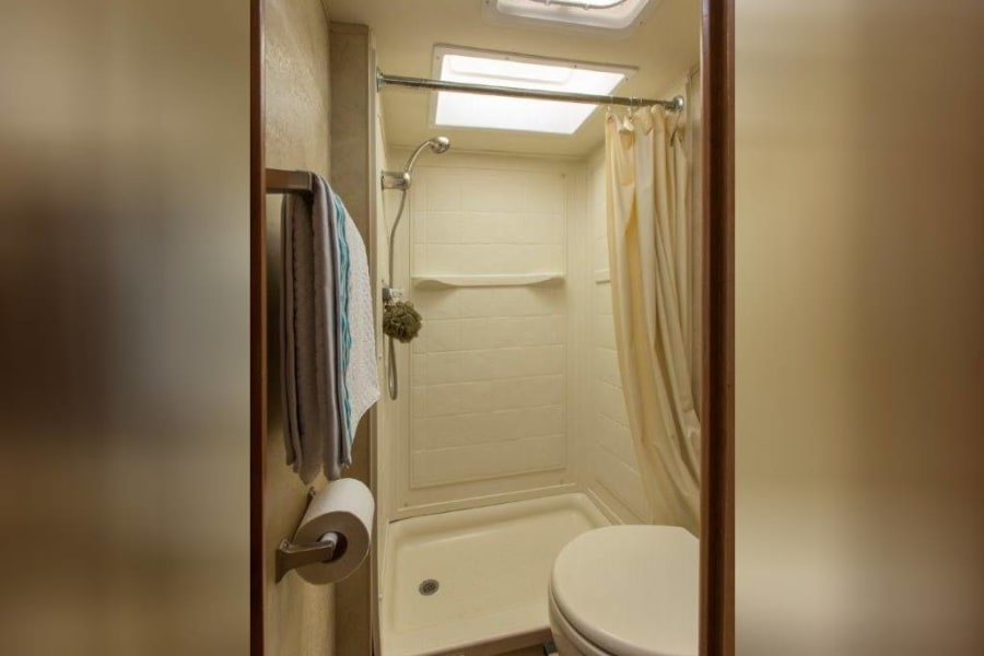 This RV rental features a compact bathroom with a shower, toilet, and essential amenities for your comfort on the go.