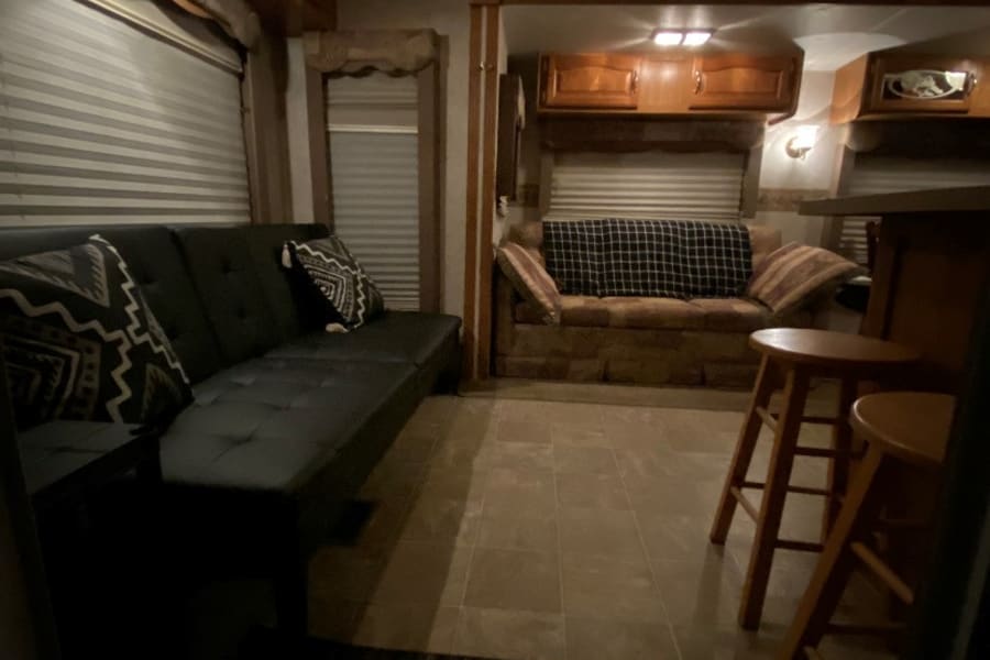 Cozy RV rental interior with warm lighting, featuring a sofa, upper cabinets, and bar stools.