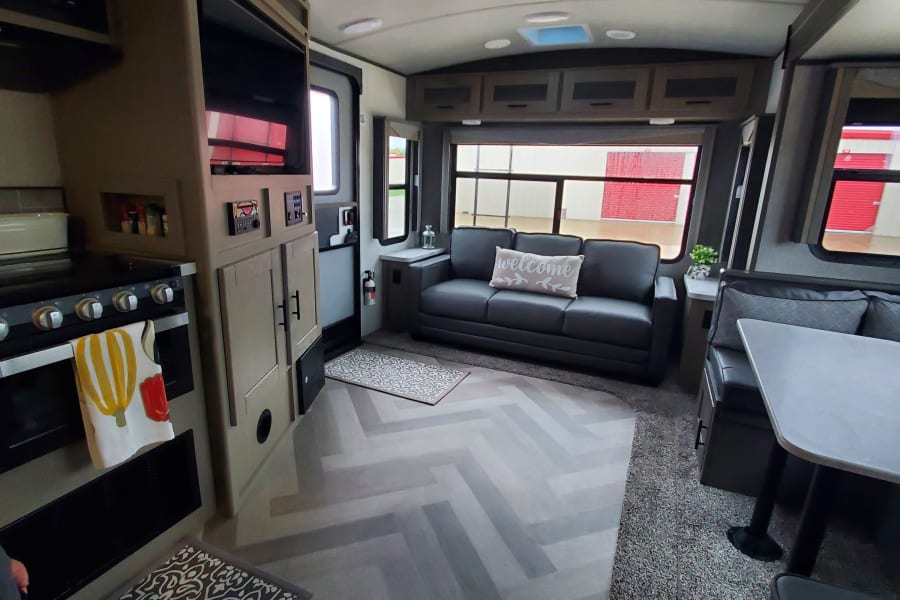 Step inside this modern RV rental! Features a full kitchen, comfy sofa, and dinette with stylish herringbone flooring.