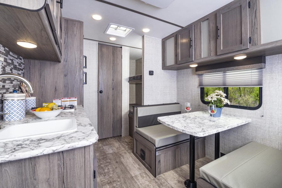 Spacious RV rental interior featuring a modern kitchen, cozy dinette, and bunk beds for comfortable travel.