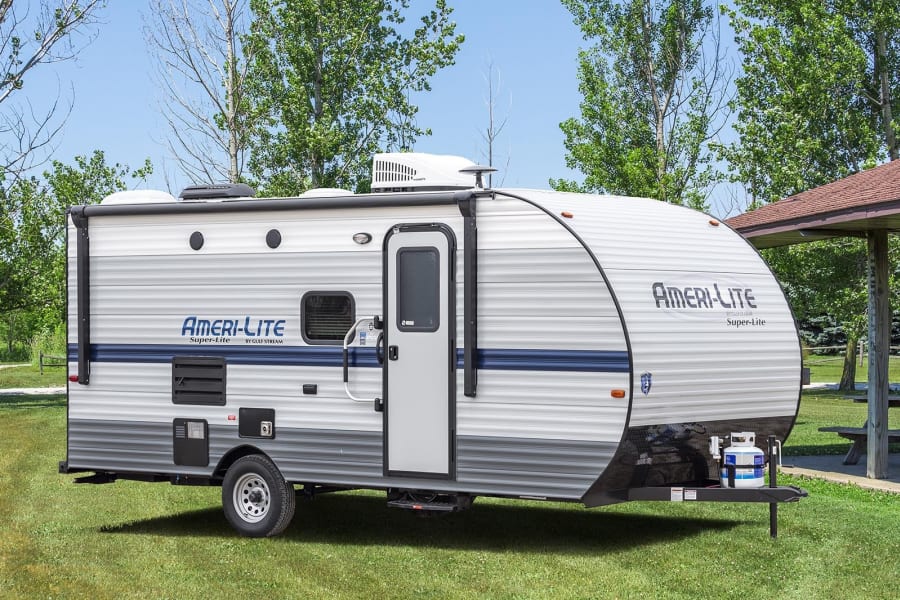 This Ameri-Lite Super-Lite travel trailer is perfect for an RV rental adventure, parked on grass for a camping trip.