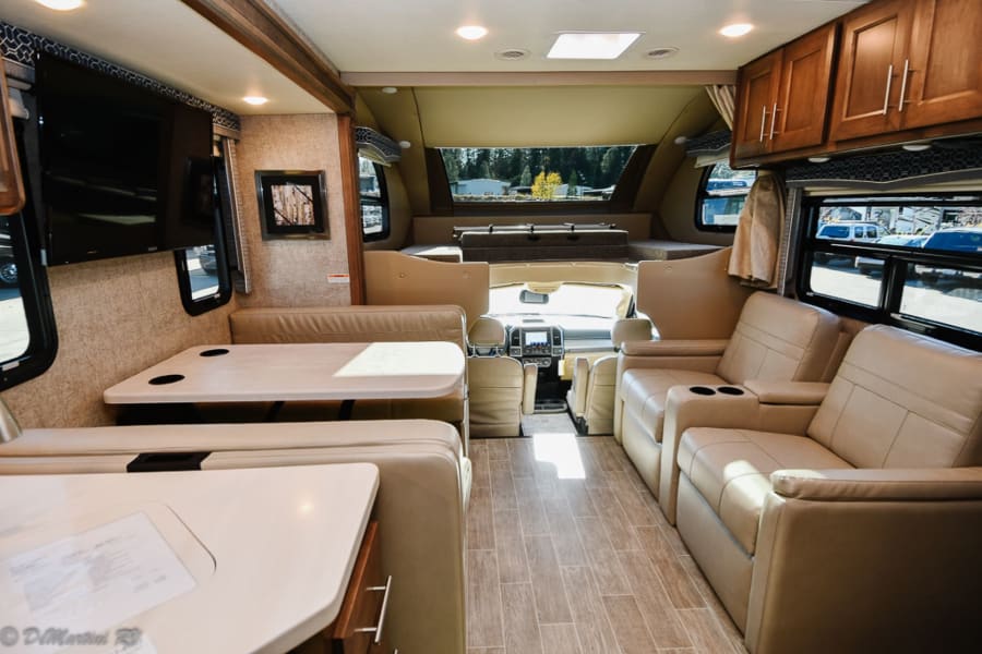Explore this RV rental's inviting interior: dining booth, comfortable lounge seating, and TV.
