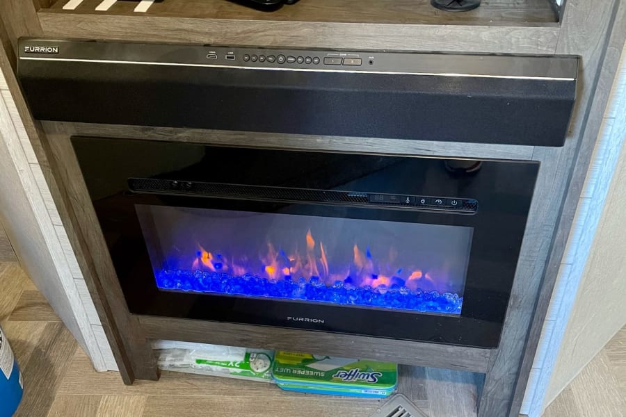 An RV rental's built-in entertainment hub: electric fireplace, Furrion soundbar, Wi-Fi ready.