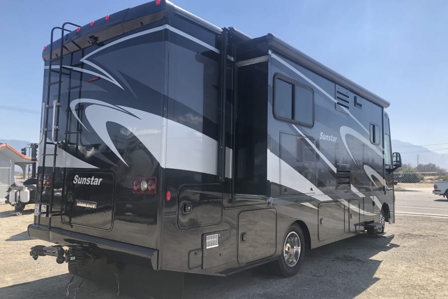 Black Winnebago Sunstar RV rental parked outdoors, showcasing its spacious exterior with an extended slide-out.