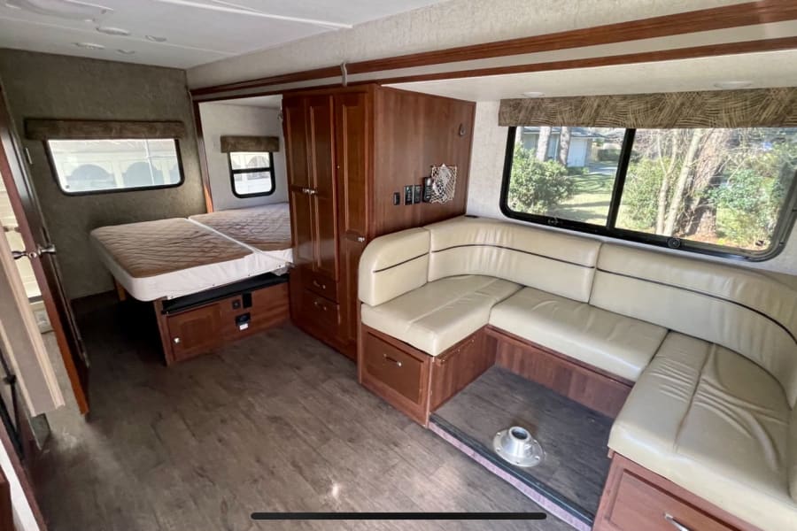 RV rental interior: inviting U-shaped dinette, comfy bed, and built-in storage solutions for a compact living space.