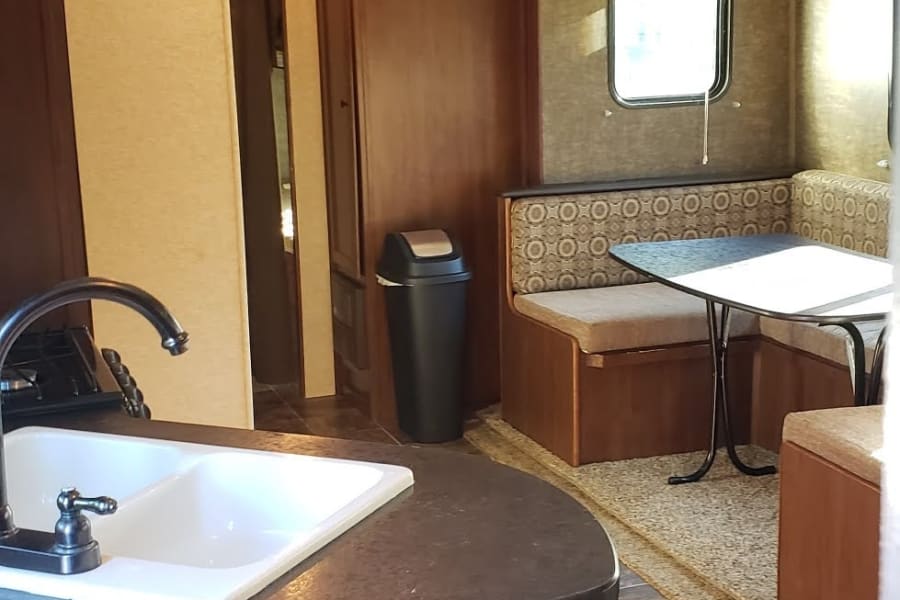 Spacious RV rental interior featuring a full kitchen with sink and a cozy dinette with booth seating.