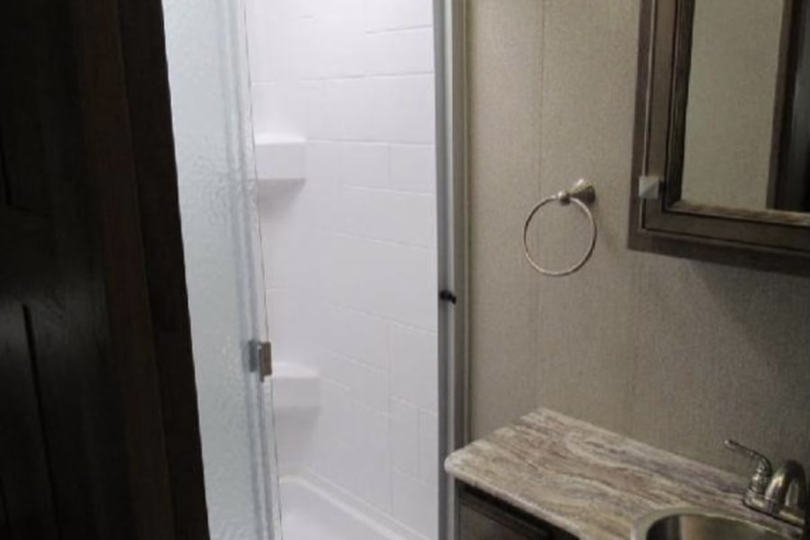 RV rental bathroom featuring a modern shower, vanity with sink, and mirrored cabinet. Clean & functional.