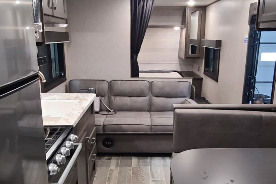 Spacious rv rental interior with kitchen, living space, dinette, and a private bedroom.