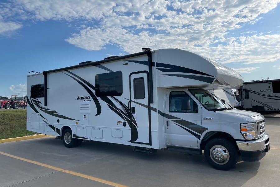 A clean white Jayco Redhawk Class C RV, perfect for rv rental adventures, parked on a sunny day under a blue sky.
