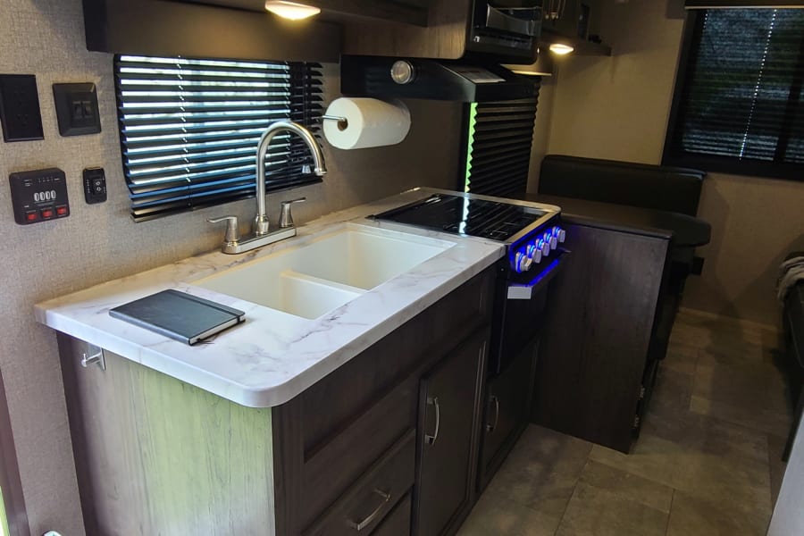 RV rental interior: A well-equipped kitchen with a double sink, stove, and dinette area for comfortable travel.