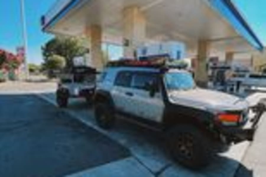 Overland adventure ready! This custom FJ Cruiser and trailer, reminiscent of an RV rental setup, fuels up at Chevron.