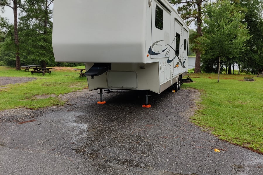 RV rental at a spacious campsite amidst tall pine trees, ready for adventure by the lake.