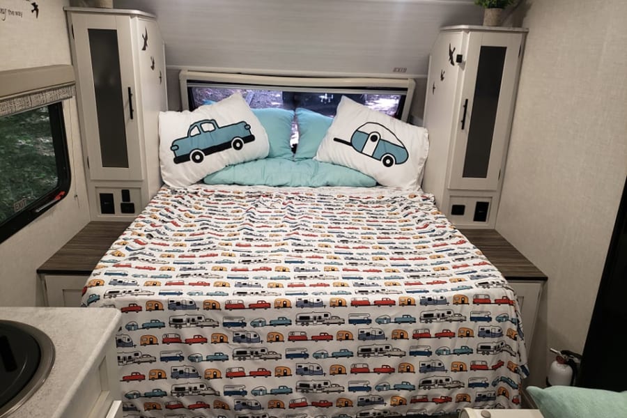RV rental: Cozy bedroom with car & camper bedding, built-in storage, window view, and fire extinguisher.
