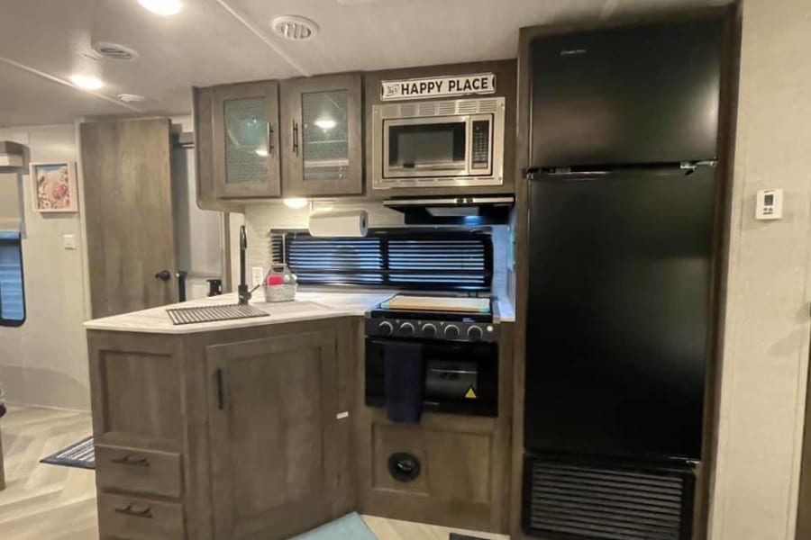 RV rental kitchen interior: sink island, stove, microwave, fridge. Ready for your next camper adventure.