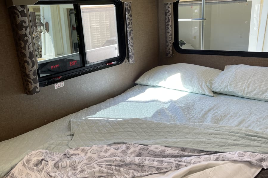 Cozy RV rental bedroom featuring neatly stored bedding, comfy pillows, and bright windows.