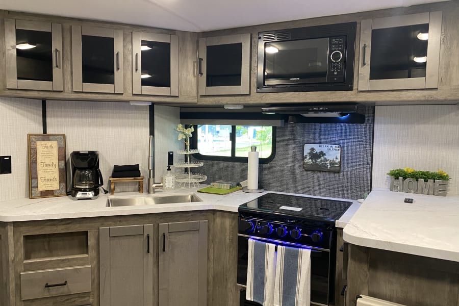 Spacious RV rental kitchen: modern design with microwave, stove, sink, and ample counter space for comfortable travel.