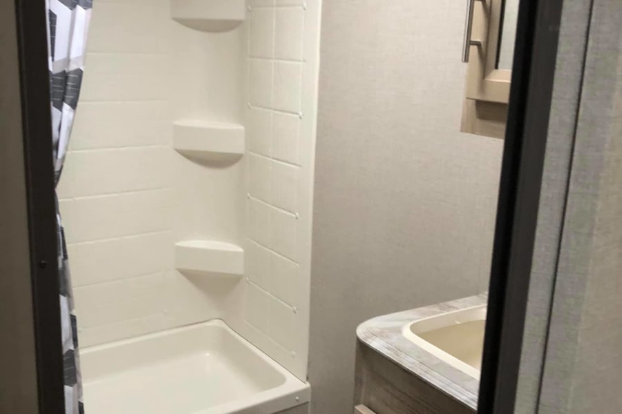 Compact RV rental bathroom with shower, toilet, and vanity. Efficient design for travel comfort.