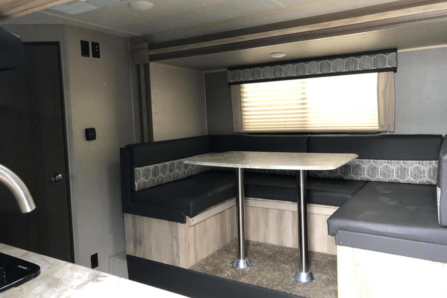 Spacious RV rental interior: U-shaped dinette, table, and window. Ideal for meals in your travel trailer.