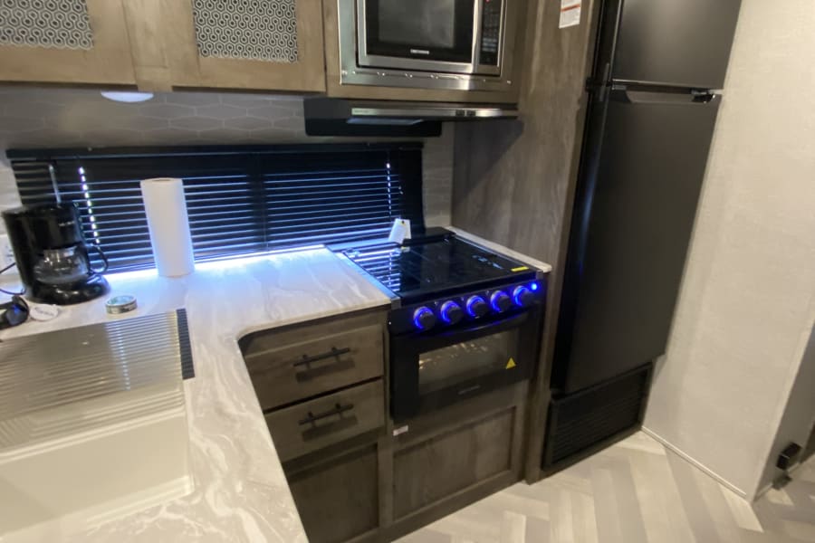 RV rental kitchen: This modern interior features a stove, microwave, and fridge, ensuring comfort for your travels.